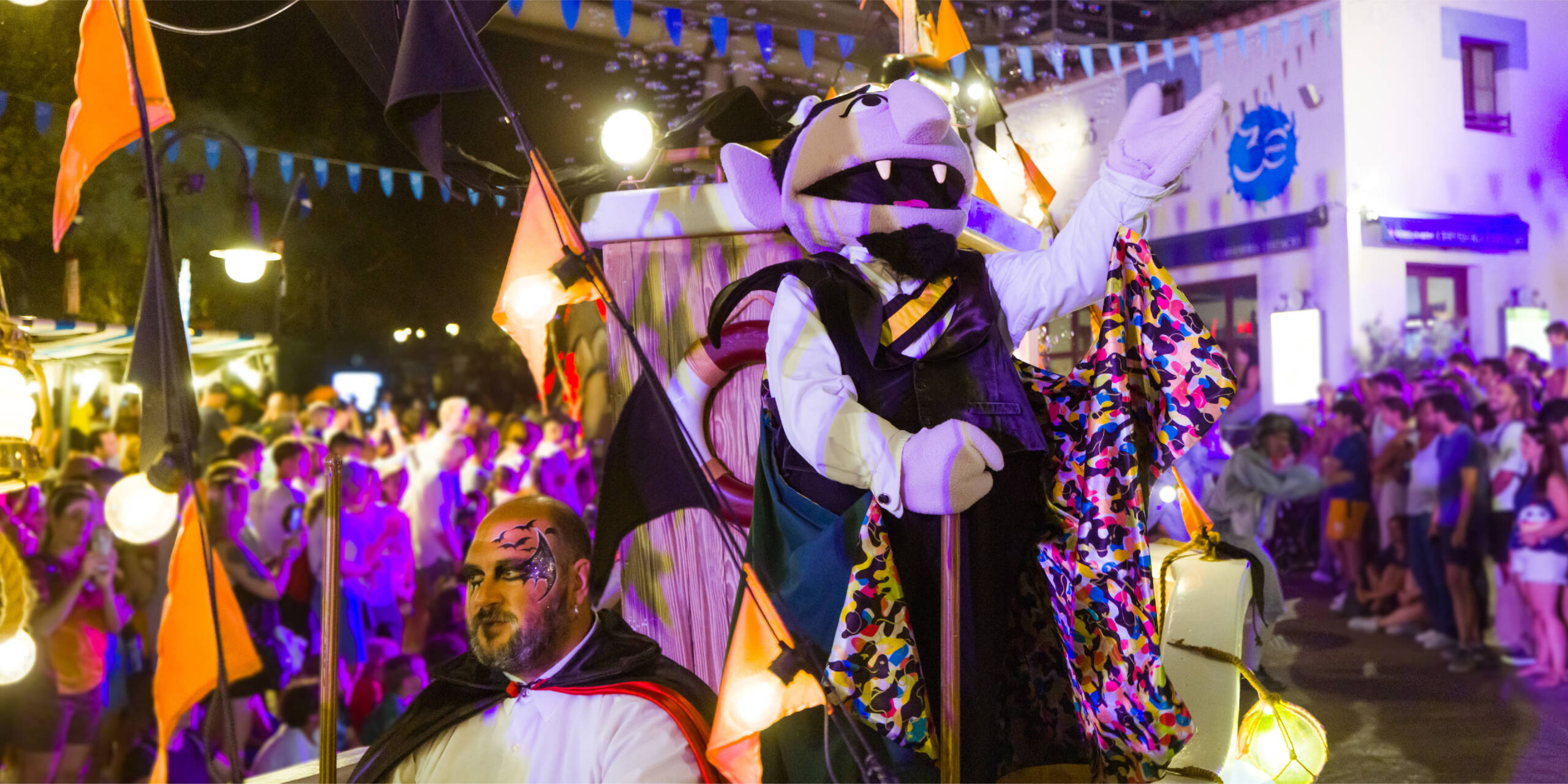 Personaje disfrazado de vampiro desfilando entre el público en una celebración nocturna de Halloween
